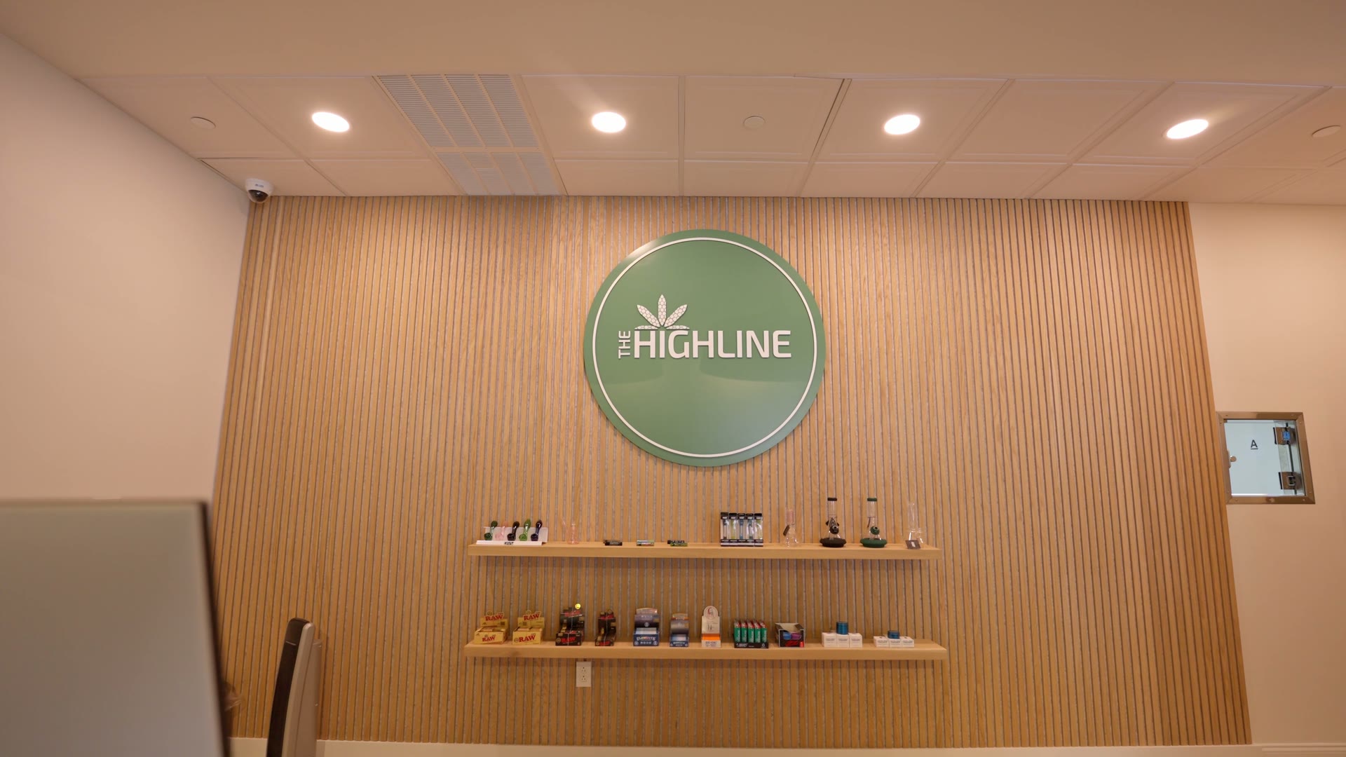 Drone push-in across The Highline's sales floor toward the circular logo medallion on the slatted wood wall